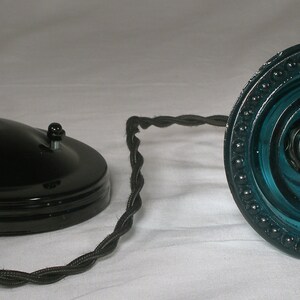 May include: A black ceiling fixture with a blue glass shade. The shade has a beaded edge and a swirling pattern.