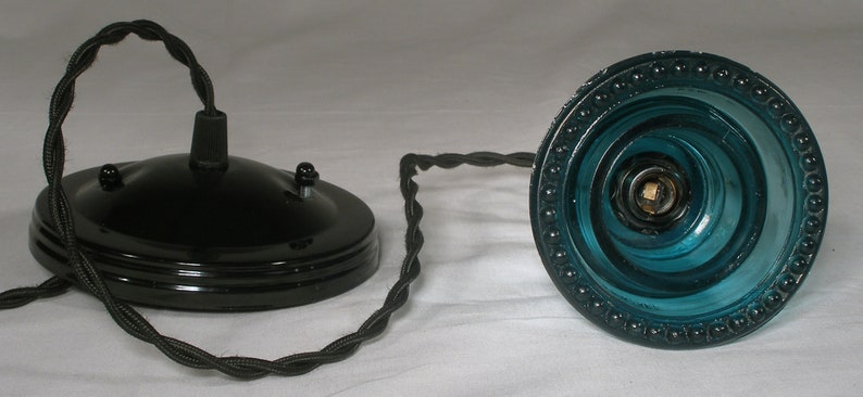 May include: A black ceiling fixture with a blue glass shade. The shade has a beaded edge and a swirling pattern.