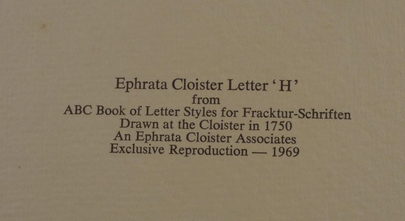 May include: Text on a beige background reads "Ephrata Cloister Letter 'H'" from "ABC Book of Letter Styles for Fracktur-Schriften" drawn in 1750. It is an exclusive reproduction from 1969 by Ephrata Cloister Associates.