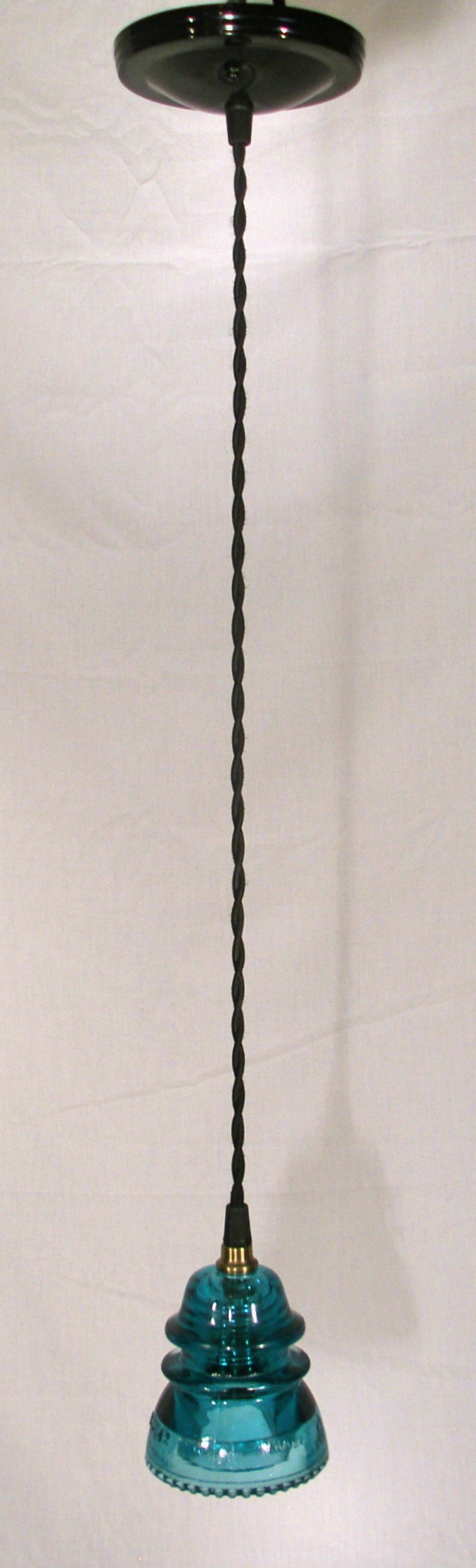 May include: A teal blue glass pendant light fixture with a black cord and a black ceiling mount.