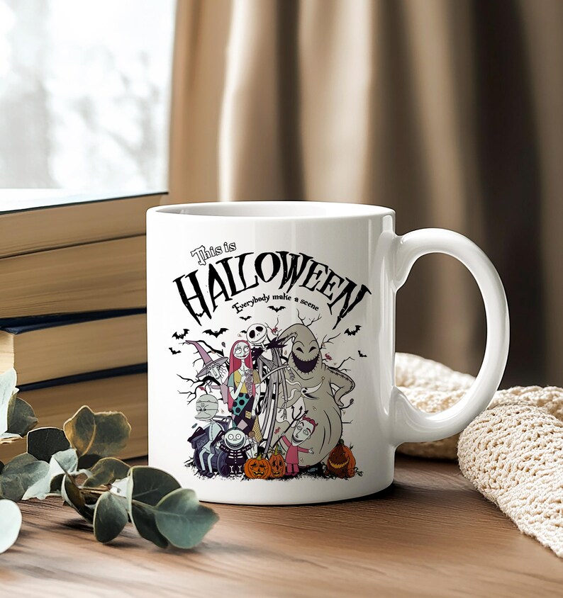 May include: White ceramic mug featuring a Halloween-themed design with characters and the text "This is Halloween." The mug has a curved handle and is decorated with bats, pumpkins, and various spooky figures.