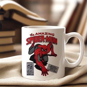 May include: White ceramic mug featuring a comic book illustration of Spider-Man in red and black. The mug has the text "the AMAZING SPIDER-MAN" in red and white. Additional text includes "FEATURING PETER PARKER SPIDER-MAN".