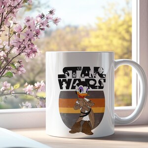 May include: White ceramic mug with a Star Wars theme, featuring a cartoon Daisy Duck character. The mug displays the Star Wars logo in black and a graphic of Daisy Duck in a brown and tan outfit. The background has a striped design in brown, orange, and grey.