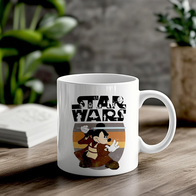 May include: White ceramic mug with a Star Wars theme. The mug displays Mickey Mouse dressed as a Jedi, wielding a lightsaber. The Star Wars logo is above the character, set against a striped background.