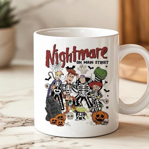 May include: White ceramic mug featuring a Halloween-themed design with the text "Nightmare on Main Street." The design includes cartoon characters dressed in skeleton costumes, pumpkins, and a tombstone. A fun and festive item for the spooky season.
