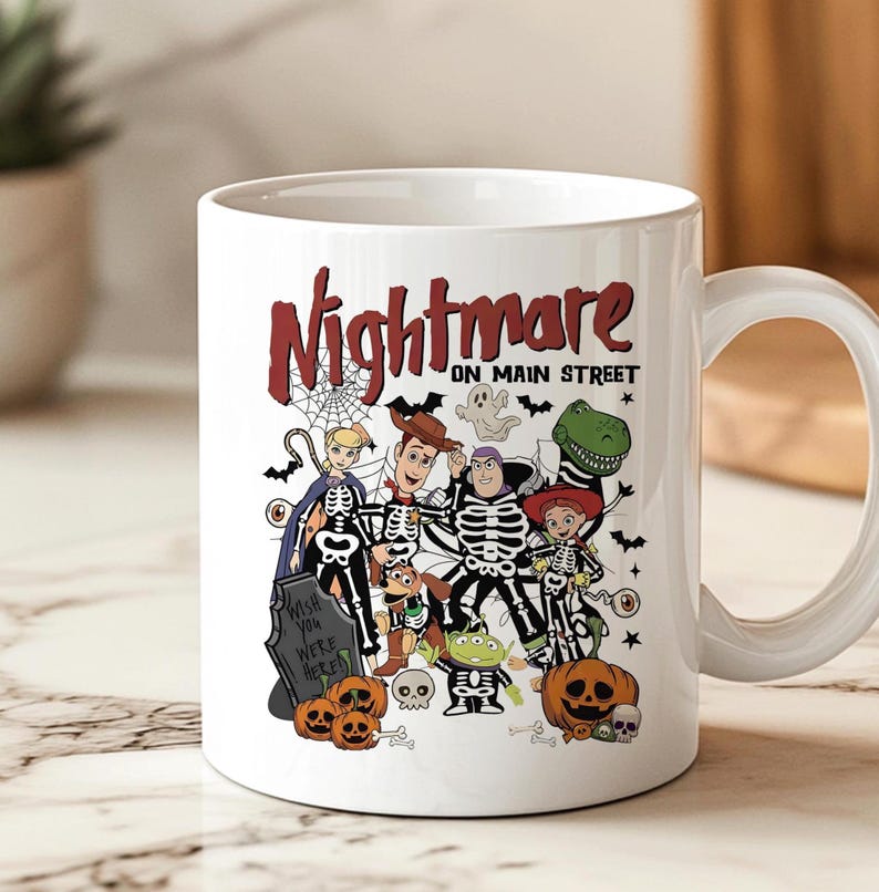 May include: White ceramic mug featuring a Halloween-themed design with the text "Nightmare on Main Street." The design includes cartoon characters dressed in skeleton costumes, pumpkins, and a tombstone. A fun and festive item for the spooky season.