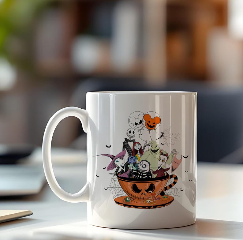 May include: White ceramic mug featuring a Halloween-themed design. The design includes characters from The Nightmare Before Christmas, inside an orange teacup with a jack-o'-lantern face. Black bats and spiderwebs are also included in the design.