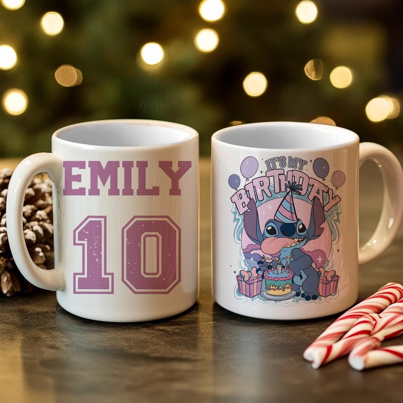 May include: Two white ceramic mugs. One mug has the name "EMILY" and the number "10" in purple. The other mug features a cartoon character with the text "IT'S MY BIRTHDAY". Candy canes are in the foreground.