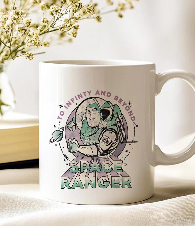 May include: White ceramic mug with a cartoon illustration of a space ranger. The mug has the text "TO INFINITY AND BEYOND" and "SPACE RANGER". The design features a space ranger in a green and white spacesuit, a planet, and stars.