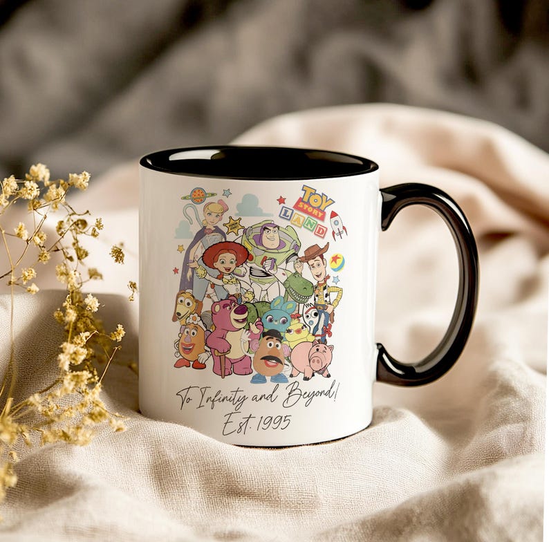 Pu&ograve; includere: Tazza in ceramica bianca con bordo e manico neri. La tazza presenta un'illustrazione colorata di personaggi del franchise Toy Story, tra cui Woody, Buzz Lightyear e Jessie. Il testo "Toy Story Land" e "To Infinity and Beyond! Est. 1995" &egrave; stampato sulla tazza.