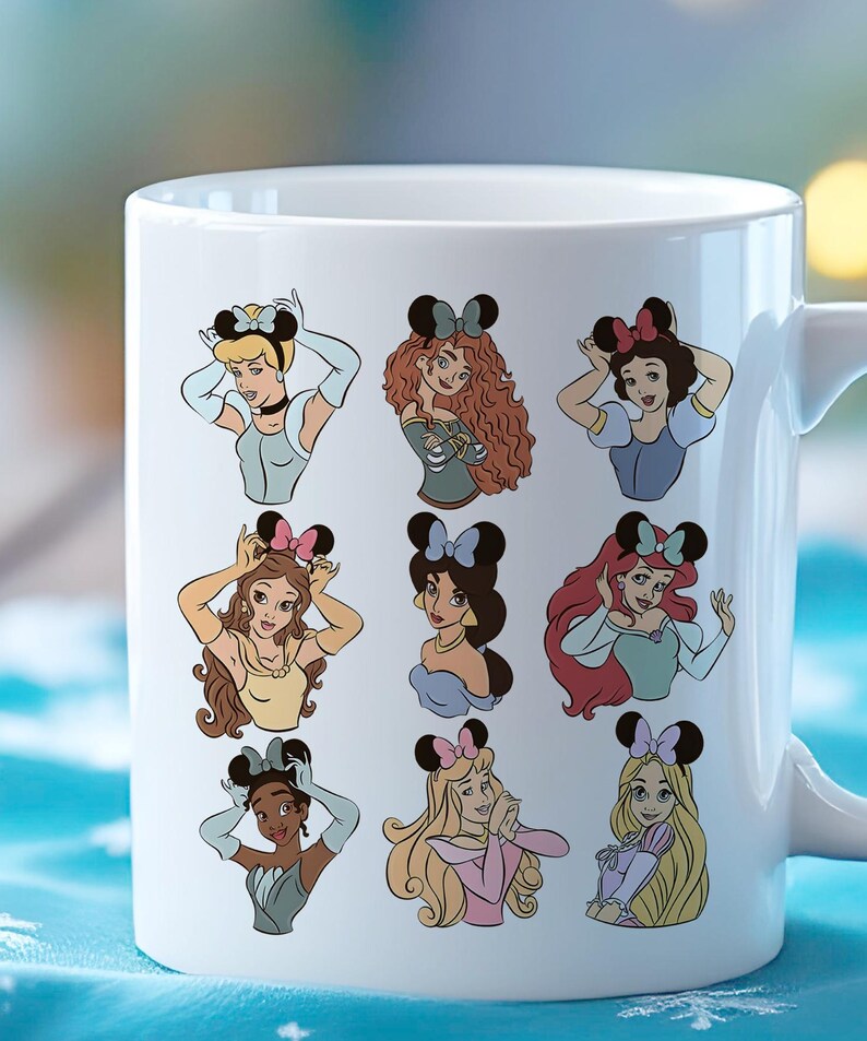 May include: White ceramic mug featuring illustrations of various cartoon princesses wearing mouse ear headbands. Each princess is depicted in a unique pose and outfit, with a colorful design. The mug has a white handle and a glossy finish.