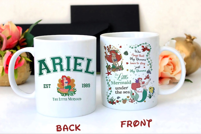May include: White ceramic mug featuring the text "ARIEL" in green collegiate lettering, with an image of Ariel the mermaid. The mug also includes the text "EST 1989" and "The Little Mermaid". The other side has a design with Ariel and the text "Who Says that My Dreams have to stay just My Dreams".