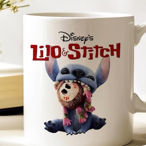 K&ouml;nnte beinhalten: Wei&szlig;er Keramikbecher mit Disney's Lilo & Stitch. Der Becher zeigt Stitch, einen blauen Au&szlig;erirdischen, der eine Puppe h&auml;lt. Der Becher hat das Disney's Lilo & Stitch-Logo in Rot. Der Becher hat einen wei&szlig;en Griff.