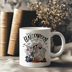 May include: White ceramic mug featuring a Halloween-themed design with the text "This is Halloween." The design includes characters and imagery from the movie, with bats and pumpkins. The mug has a white handle and is set against a neutral background.