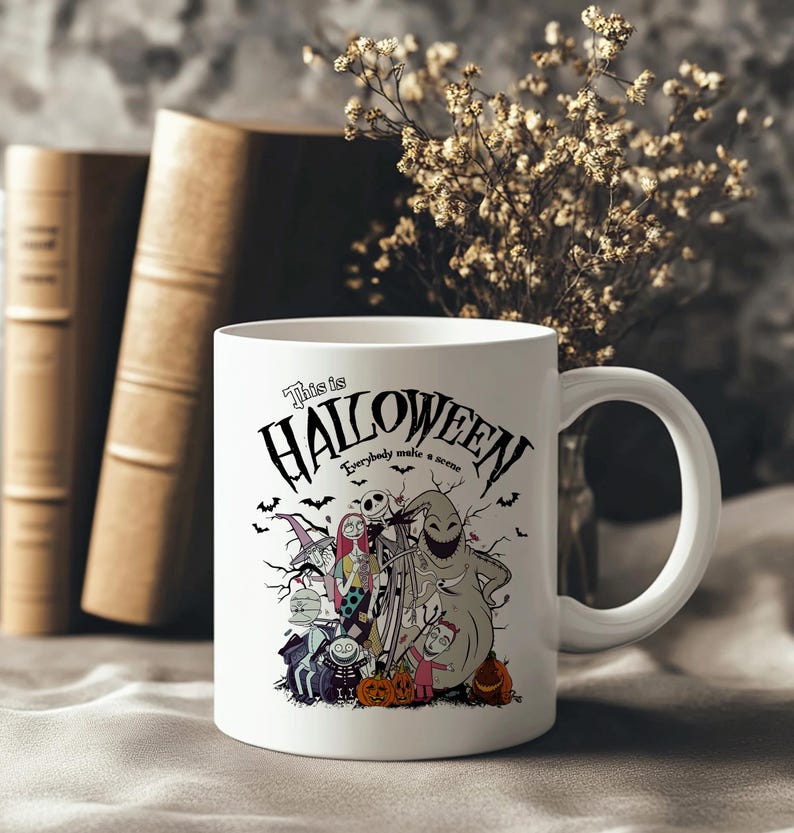 May include: White ceramic mug featuring a Halloween-themed design with the text "This is Halloween." The design includes characters and imagery from the movie, with bats and pumpkins. The mug has a white handle and is set against a neutral background.