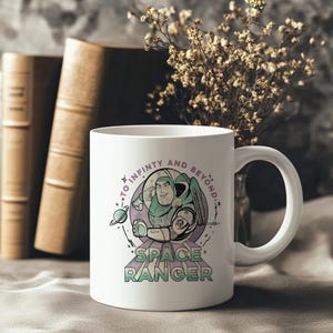 May include: White ceramic mug with a graphic of Buzz Lightyear in his space ranger suit, and the text "TO INFINITY AND BEYOND" and "SPACE RANGER". The mug has a curved handle. The background is neutral.