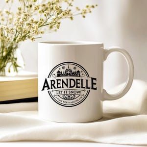May include: White ceramic mug with a black graphic that reads "Arendelle" with a castle illustration and the text "Let it Snow! A place worth melting for". The mug has a curved handle and is set on a white surface.