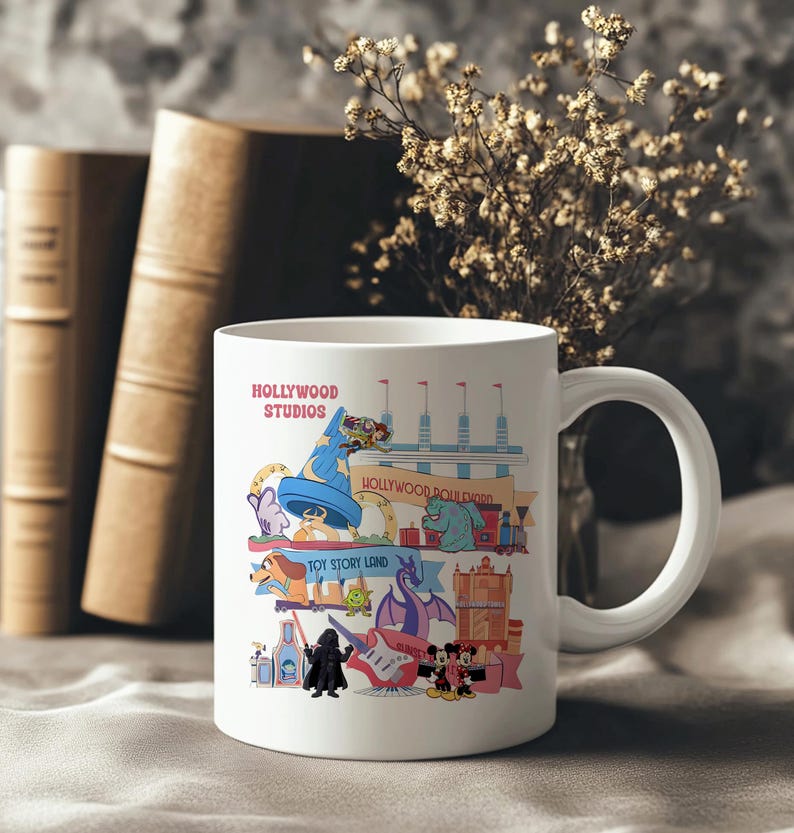 K&ouml;nnte beinhalten: Wei&szlig;er Keramikbecher mit einer farbenfrohen Illustration von Hollywood Studios Attraktionen und Charakteren. Der Becher tr&auml;gt den Text "HOLLYWOOD STUDIOS" und Bilder von ikonischen Charakteren und Wahrzeichen. Der Becher hat einen gro&szlig;en, gebogenen Griff.