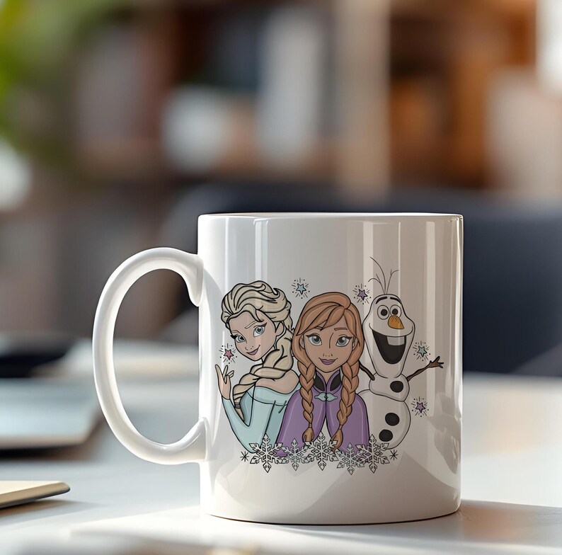 Puede incluir: Taza de cer&aacute;mica blanca con Elsa, Anna y Olaf de la pel&iacute;cula de animaci&oacute;n "Frozen". Los personajes est&aacute;n representados en un estilo de dibujos animados colorido, con copos de nieve y estrellas. La taza tiene un asa curva.