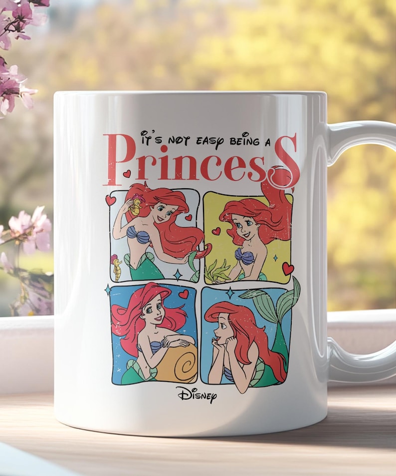 Pode incluir: Caneca de cer&acirc;mica branca com uma ilustra&ccedil;&atilde;o colorida de Ariel de A Pequena Sereia. A caneca apresenta o texto "It's not easy being a Princess" e um logotipo da Disney.