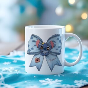 Pu&ograve; includere: Tazza in ceramica bianca con un fiocco blu a pois bianchi e un personaggio dei cartoni animati. Il personaggio &egrave; blu con orecchie rosa e una corona. La parola "Ohana" &egrave; scritta sul fiocco e c'&egrave; anche un fiore di ibisco.