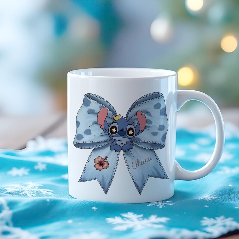 Pu&ograve; includere: Tazza in ceramica bianca con un fiocco blu a pois bianchi e un personaggio dei cartoni animati. Il personaggio &egrave; blu con orecchie rosa e una corona. La parola "Ohana" &egrave; scritta sul fiocco e c'&egrave; anche un fiore di ibisco.