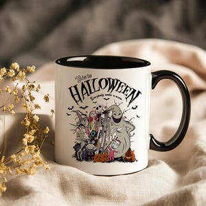 May include: White ceramic mug with a black interior and handle. The mug features a Halloween-themed design with characters and the text "This is Halloween." Bats and pumpkins are also included in the design.