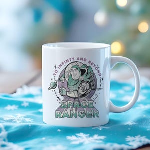 May include: White ceramic mug with a cartoon space ranger illustration and the text "TO INFINITY AND BEYOND" and "SPACE RANGER". The design features a planet and stars in green, purple, and white. A classic mug for fans.