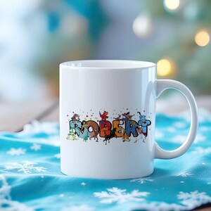 May include: White ceramic mug with the name "ROBERT" in colorful, cartoon-style letters. Each letter is decorated with different cartoon characters. The mug has a curved handle and is set against a blurred background.