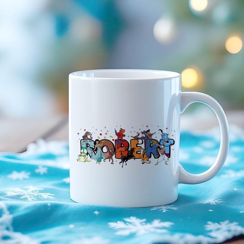 May include: White ceramic mug with the name "ROBERT" in colorful, cartoon-style letters. Each letter is decorated with different cartoon characters. The mug has a curved handle and is set against a blurred background.