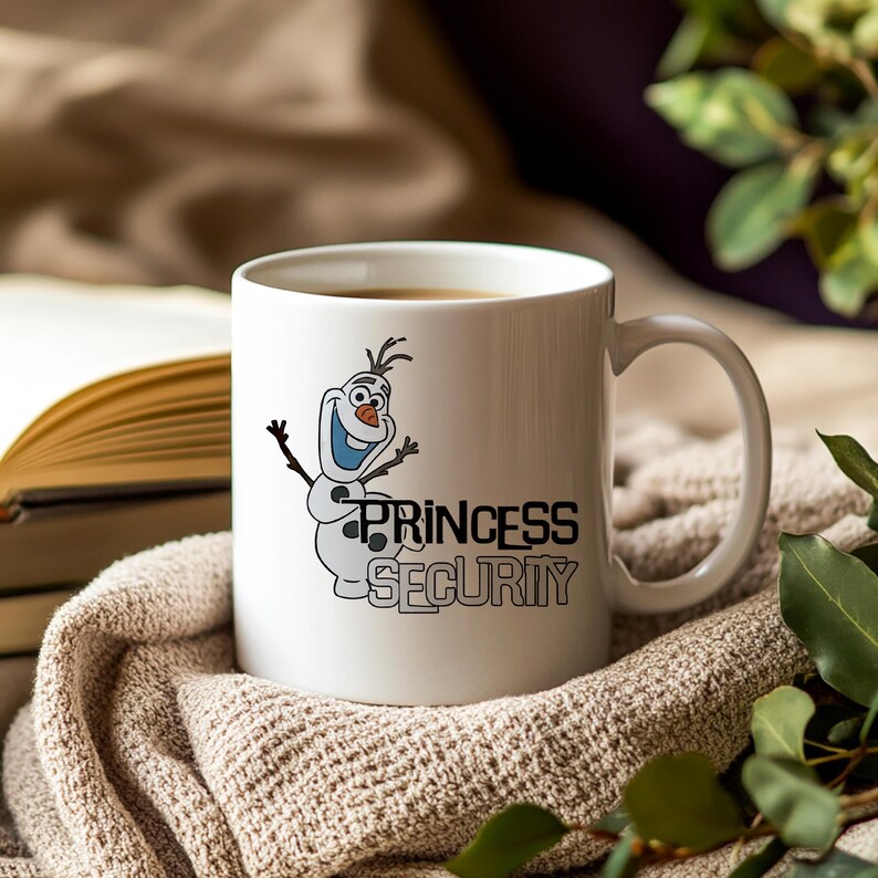 May include: White ceramic mug featuring a cartoon image of Olaf the snowman with the text "PRINCESS SECURITY" in black. The mug is filled with a hot beverage and rests on a beige knitted blanket, with a book in the background.
