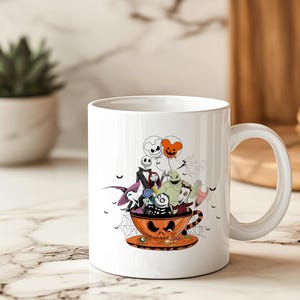 May include: White ceramic mug featuring a Halloween-themed design. The design includes characters from The Nightmare Before Christmas inside an orange teacup with a jack-o'-lantern face. The mug has a large handle and a matching saucer.