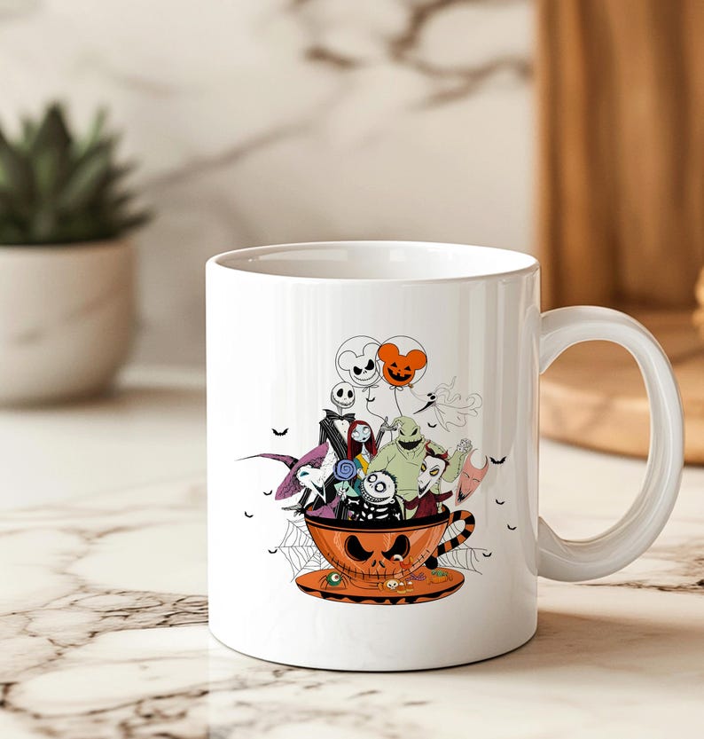 May include: White ceramic mug featuring a Halloween-themed design. The design includes characters from The Nightmare Before Christmas inside an orange teacup with a jack-o'-lantern face. The mug has a large handle and a matching saucer.