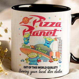 May include: White ceramic mug with a black rim and handle. The mug features a colorful illustration of the Pizza Planet restaurant from the Toy Story franchise. The text "Pizza Planet" is written in red and white with a red star and a pizza slice above the text. Three green alien characters are featured in the illustration. The text "Out of this world quality" and "Serving your local star cluster" is written in black at the bottom of the mug.