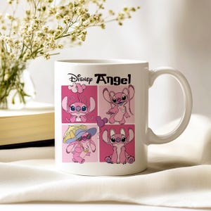 Pu&ograve; includere: Tazza in ceramica bianca con manico curvo, raffigurante il personaggio Disney Angel in quattro quadrati rosa. La tazza ha le parole "Disney Angel" in nero. Sullo sfondo un vaso di fiori e un libro.