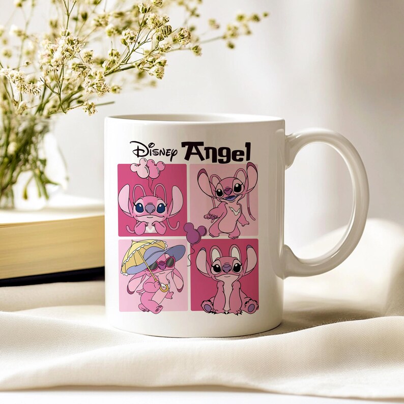 Pu&ograve; includere: Tazza in ceramica bianca con manico curvo, raffigurante il personaggio Disney Angel in quattro quadrati rosa. La tazza ha le parole "Disney Angel" in nero. Sullo sfondo un vaso di fiori e un libro.