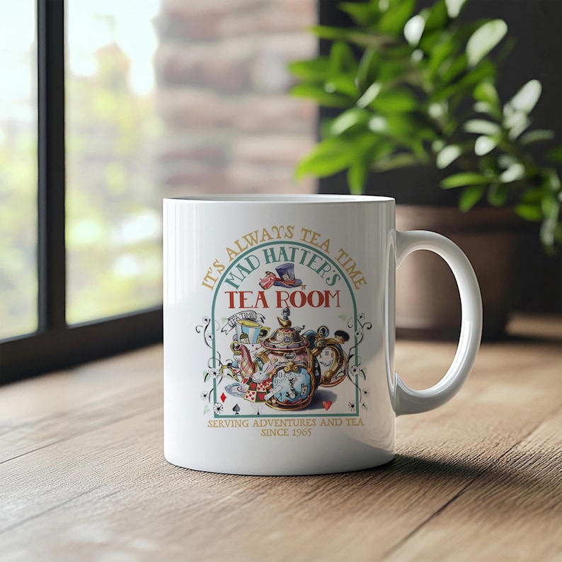 Puede incluir: Taza de cer&aacute;mica blanca con un dise&ntilde;o caprichoso que presenta una tetera, naipes y el texto "Mad Hatter's Tea Room". La taza tambi&eacute;n incluye el texto "It's always tea time" y "Serving adventures and tea since 1965."