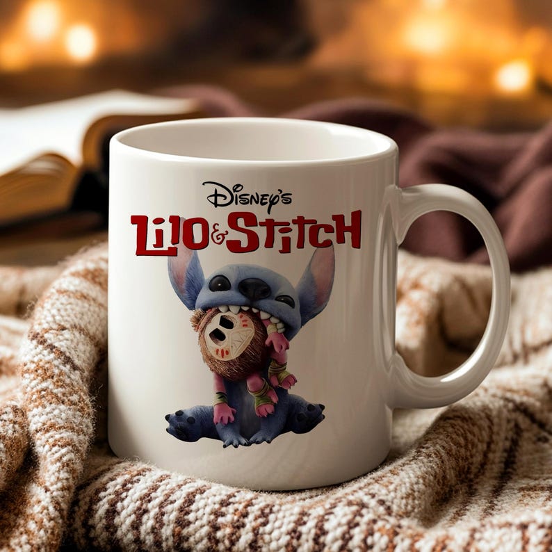 K&ouml;nnte beinhalten: Wei&szlig;e Keramik-Tasse mit Disney's Lilo & Stitch. Die Tasse zeigt das Titellogo in Rot und eine blaue Stitch-Figur, die ein braunes und rosa Pl&uuml;schtier h&auml;lt. Die Tasse hat einen gebogenen Griff.