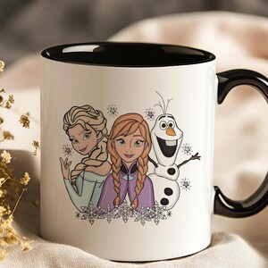 Puede incluir: Taza de cer&aacute;mica blanca con interior y asa negros. La taza presenta una colorida ilustraci&oacute;n de Elsa, Anna y Olaf de la pel&iacute;cula Frozen. El dise&ntilde;o incluye copos de nieve y estrellas, ideal para los fans de la pel&iacute;cula.