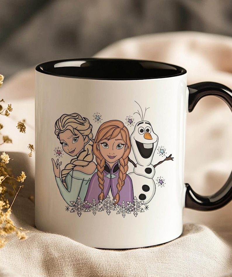 Puede incluir: Taza de cer&aacute;mica blanca con interior y asa negros. La taza presenta una colorida ilustraci&oacute;n de Elsa, Anna y Olaf de la pel&iacute;cula Frozen. El dise&ntilde;o incluye copos de nieve y estrellas, ideal para los fans de la pel&iacute;cula.