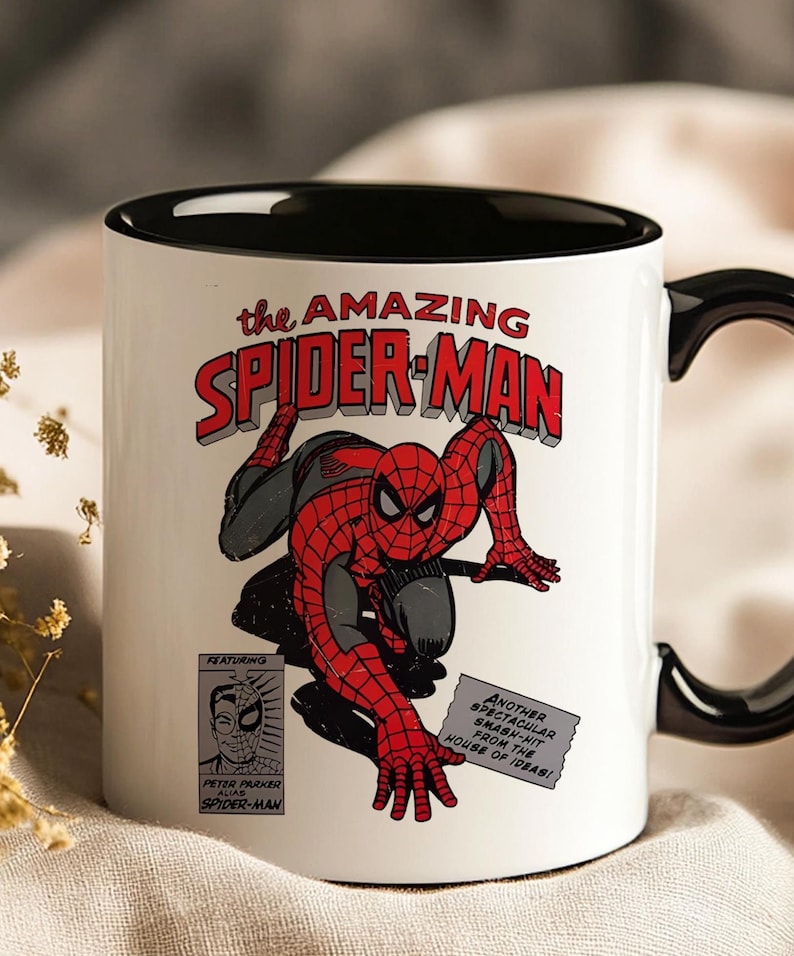 May include: White ceramic mug with a black interior and handle. The mug features a comic book illustration of Spider-Man in red and black, with the text "the AMAZING SPIDER-MAN". Additional text includes "FEATURING" and "PETER PARKER ALIAS SPIDER-MAN".