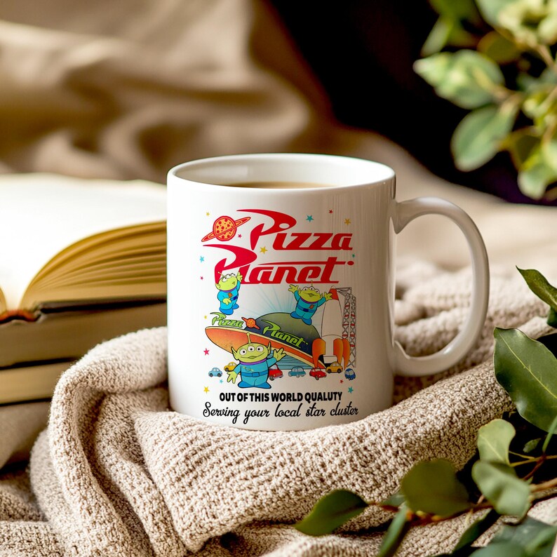 May include: White ceramic mug with a colorful graphic of the Pizza Planet logo and characters from the Toy Story franchise. The text on the mug reads "Pizza Planet", "Out of this world quality", and "Serving your local star cluster".