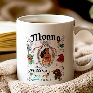 May include: A white ceramic coffee mug with a design featuring Moana from the Disney movie Moana. The design includes Moana in a frame with a pink ribbon, a rooster, a pig, a crab, and a green plant. The text on the mug reads 'Moana', 'Disney Moana', and 'Est. 2016'.