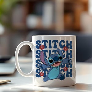 Puede incluir: Taza de cer&aacute;mica blanca con un personaje de dibujos animados azul con orejas grandes y la palabra "STITCH" en texto azul. Acentos de flores rojas est&aacute;n colocados en todo el dise&ntilde;o. La taza tiene un asa blanca y est&aacute; sobre un fondo borroso.