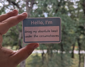 May include: A light blue card with the text "Hello, I'm doing my absolute best under the circumstances" written in black.