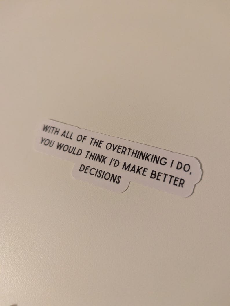 May include: A white sticker with the text: "WITH ALL OF THE OVERTHINKING I DO, YOU WOULD THINK I'D MAKE BETTER DECISIONS" in black, sans-serif font. The sticker has a rounded, cloud-like shape.