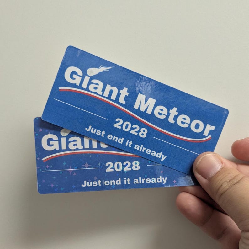 May include: Two blue rectangular cards with the text "Giant Meteor 2028" and "Just end it already" in white. The cards have a red and white stripe design and a starry background.