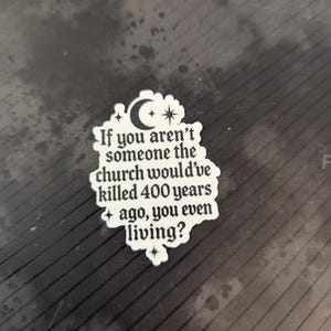 May include: A white sticker with a black, gothic-style font that reads, "If you aren't someone the church would've killed 400 years ago, you even living?" The sticker has a crescent moon and star design.