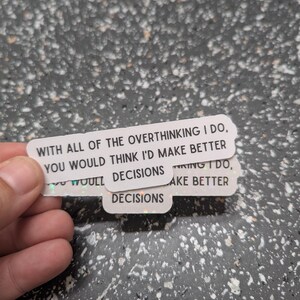 May include: White, rectangular stickers with holographic edges. The stickers have the text: "WITH ALL OF THE OVERTHINKING I DO, YOU WOULD THINK I'D MAKE BETTER DECISIONS."