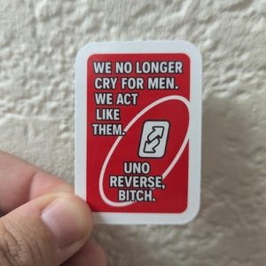 May include: A red Uno card with white text that reads "WE NO LONGER CRY FOR MEN. WE ACT LIKE THEM. UNO REVERSE, BITCH." The card also features the Uno reverse symbol.